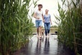 Young adult couple running barefoot on wooden path by the river with their dog, holding hands Royalty Free Stock Photo