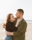 Young adult couple standing on beach, looking each other. Man embracing laughing woman Royalty Free Stock Photo