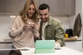 Young adult couple using together a tablet from home in a modern kitchen. Happy joyful man and woman on a video call