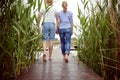 Young adult couple walking barefoot toward lake, holding hands Royalty Free Stock Photo