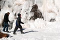 A young adult couple walks past a frozen waterfall