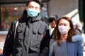 A young adult couple walks together while wearing face masks