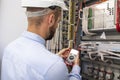 Young adult electrician builder engineer inspecting electric equipment in distribution fuse box