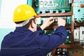 Adult electrician builder engineer worker testing electronics in switch board