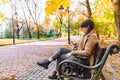 young adult fashion woman sitting at city park bench in autumn fall season Royalty Free Stock Photo