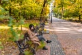 young adult fashion woman sitting at city park bench in autumn fall season Royalty Free Stock Photo