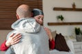 Young adult female cancer patient hugging her husband at home after treatment in hospital. Cancer and family support. Royalty Free Stock Photo