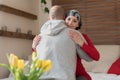 Young adult female cancer patient hugging her husband at home after treatment in hospital. Cancer and family support. Royalty Free Stock Photo