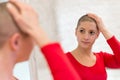 Young adult female cancer patient looking in the mirror.