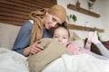 Young adult female cancer patient spending time with her daughter at home, relaxing on the couch. Royalty Free Stock Photo