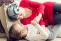 Young adult female cancer patient spending time with her daughter at home, relaxing on couch. Cancer and family support concept.