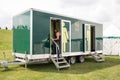 Young adult female looking at her mobile phone while walking up the steps into public toilets on a trailer