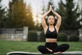 Young adult female in sportswear doing Yoga in the park outdoor, healthy woman sitting on grass and meditation with lotus pose in Royalty Free Stock Photo