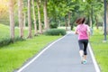 Young adult female in sportswear running in the park outdoor, runner woman jogging on the road, asian Athlete walking and exercise Royalty Free Stock Photo