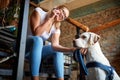 Young adult female talking on a cell phone, smiling, sitting on stairs cuddling her dog