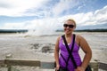 Young adult female tourist stands near Spasm Geyser in Yellowstone National Park