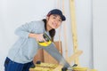 Young adult female woodworker hand sawing in workshop