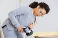Young adult female worker grinding plank with electric grinder