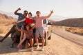 Young adult friends on road trip have fun posing by the car Royalty Free Stock Photo