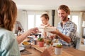 Young adult friends serving each other lunch at a dinner table, close up