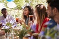 Young adult friends socialising at a table in a garden