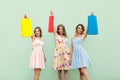 Young adult girl in dress, showing her bags after shopping. Hands up and holding her colorful bags. Royalty Free Stock Photo