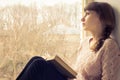 Young adult girl reading book near the window