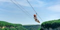 young adult girl rides a zipline in the mountains against a blue sky in thailand Royalty Free Stock Photo