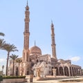 Adult girl wearing a hijab and an Islamic dress stands in front of the Mosque