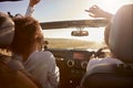 Young adult girlfriends driving with sunroof open, back view