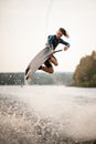 young adult guy jumps spectacularly on wakeboard above the water with splashes Royalty Free Stock Photo