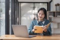 Young adult happy smiling Asian student wearing headphones talking on online chat meeting using laptop in university Royalty Free Stock Photo