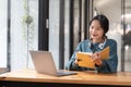 Young adult happy smiling Asian student wearing headphones talking on online chat meeting using laptop in university Royalty Free Stock Photo