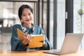 Young adult happy smiling Asian student wearing headphones talking on online chat meeting using laptop in university Royalty Free Stock Photo