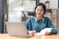 Young adult happy smiling Asian student wearing headphones talking on online chat meeting using laptop in university Royalty Free Stock Photo