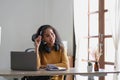 Young adult happy smiling Hispanic Asian student wearing headphones talking on online chat meeting using laptop in university Royalty Free Stock Photo