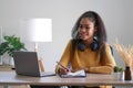 Young adult happy smiling Hispanic Asian student wearing headphones talking on online chat meeting using laptop in university Royalty Free Stock Photo