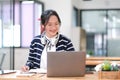 Young adult happy smiling Hispanic Asian student wearing headphones talking on online chat meeting using laptop in Royalty Free Stock Photo