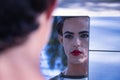 Young adult Hispanic transsexual girl looking in a mirror as a child after applying makeup. Transgender concept, inclusion and