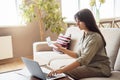 Young indian woman holding bill using laptop paying bill online at home. Royalty Free Stock Photo