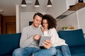 Young adult interracial couple sitting on couch, using tablet computer Royalty Free Stock Photo