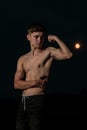 Young adult male flexing his arm muscles at twilight Royalty Free Stock Photo