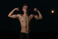 Young adult male flexing his arm muscles at twilight Royalty Free Stock Photo