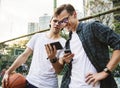 Young adult male friends on the basketball court using smartphones millennials concept Royalty Free Stock Photo