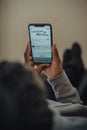 Young adult male holding an iPhone in hand while looking attentively at the screen