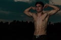 Young adult male flexing his muscles at twilight Royalty Free Stock Photo