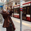 Young adult male musician playing a trumpet in a bus stop in an urban setting.