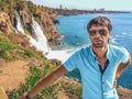 Young adult male tourist posing in front of Lower Duden Waterfall in Antalya