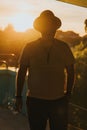 Young adult male wearing a fedora hat stands on a balcony, shot from behind Royalty Free Stock Photo