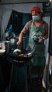 Young adult male wearing a protective face mask standing in front of a charcoal grill outdoors